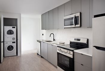 A modern kitchen with a washing machine and a microwave.